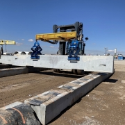 two Kenco Barrier lifts in unison lifting an oversized concrete barrier wall with an industrial forklift