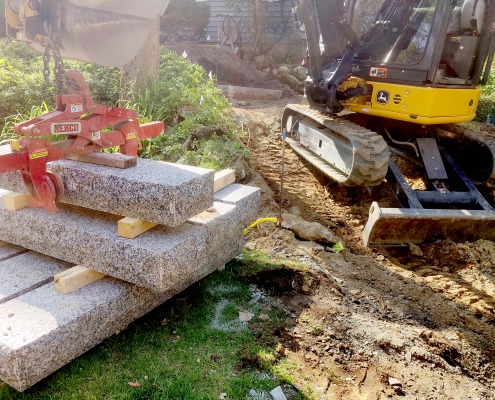 Mini excavator installing granite stones to a homeowner's walkway.