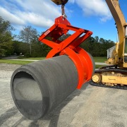 Large pipe clamping device gripping a concrete pipe by means of an excavator.