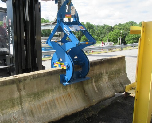 blue barrier clamp picking up concrete wall in parking lot