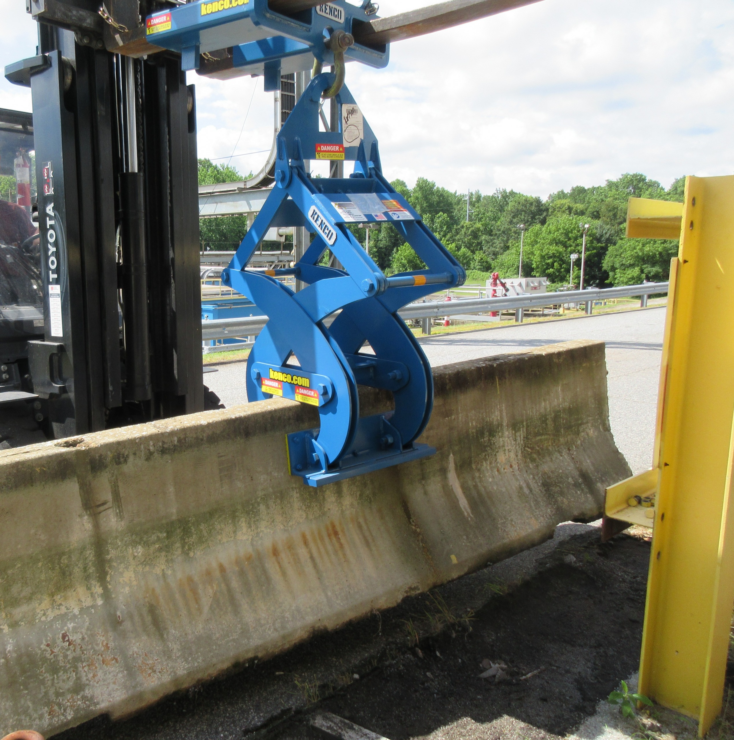 blue barrier clamp picking up concrete wall in parking lot