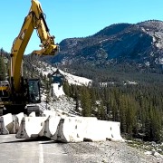 Kenco Barrier Lift picking up concrete jersey barricades in Yellowstone National Park with a CAT excavator