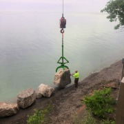 moving large boulder in place next to water for erosion control