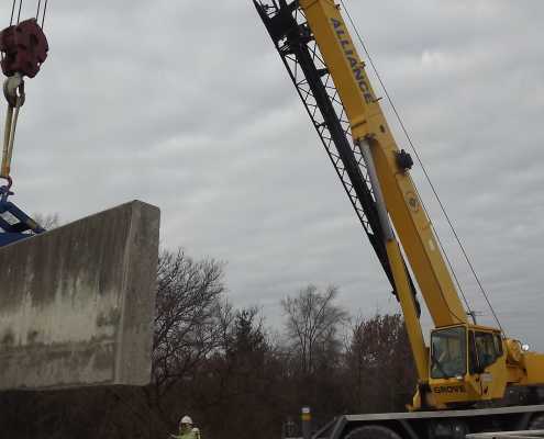 crane lifting a concrete wall in waste water treatment plant with a blue scissor clamping device