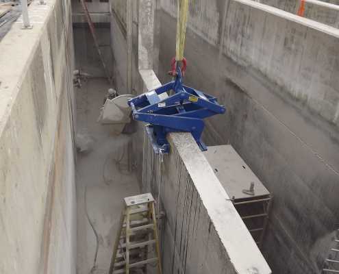 Kenco barrier lift resting on top of tall concrete wall inside of a waste water treatment plant