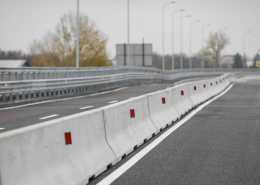 A selective focus shot of a long row of concrete barriers lining the side of an empty major highway.