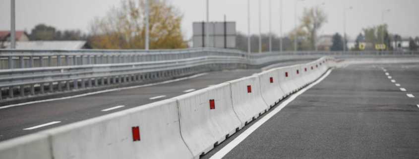 A selective focus shot of a long row of concrete barriers lining the side of an empty major highway.