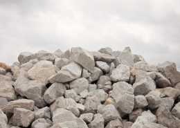 A large pile of medium-sized, grey boulders with an equally grey, cloudy sky looming in the background.
