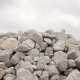 A large pile of medium-sized, grey boulders with an equally grey, cloudy sky looming in the background.