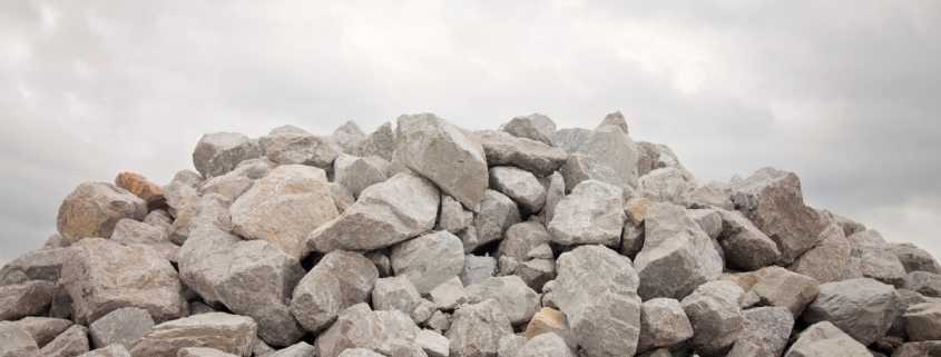 A large pile of medium-sized, grey boulders with an equally grey, cloudy sky looming in the background.