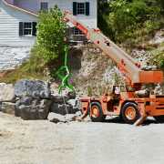 telehandler being used for moving boulders with a green triple tined lifting tool