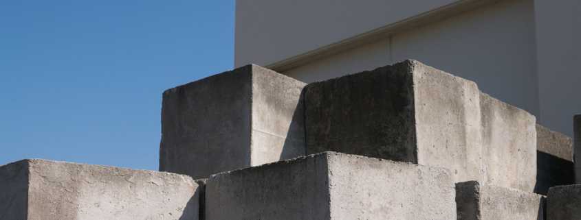 Large concrete blocks stacked on top of one another in a pile. Some blocks have metal handles in them.