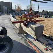 construction worker guiding the installation of concrete precast benches in a row on a jobsite