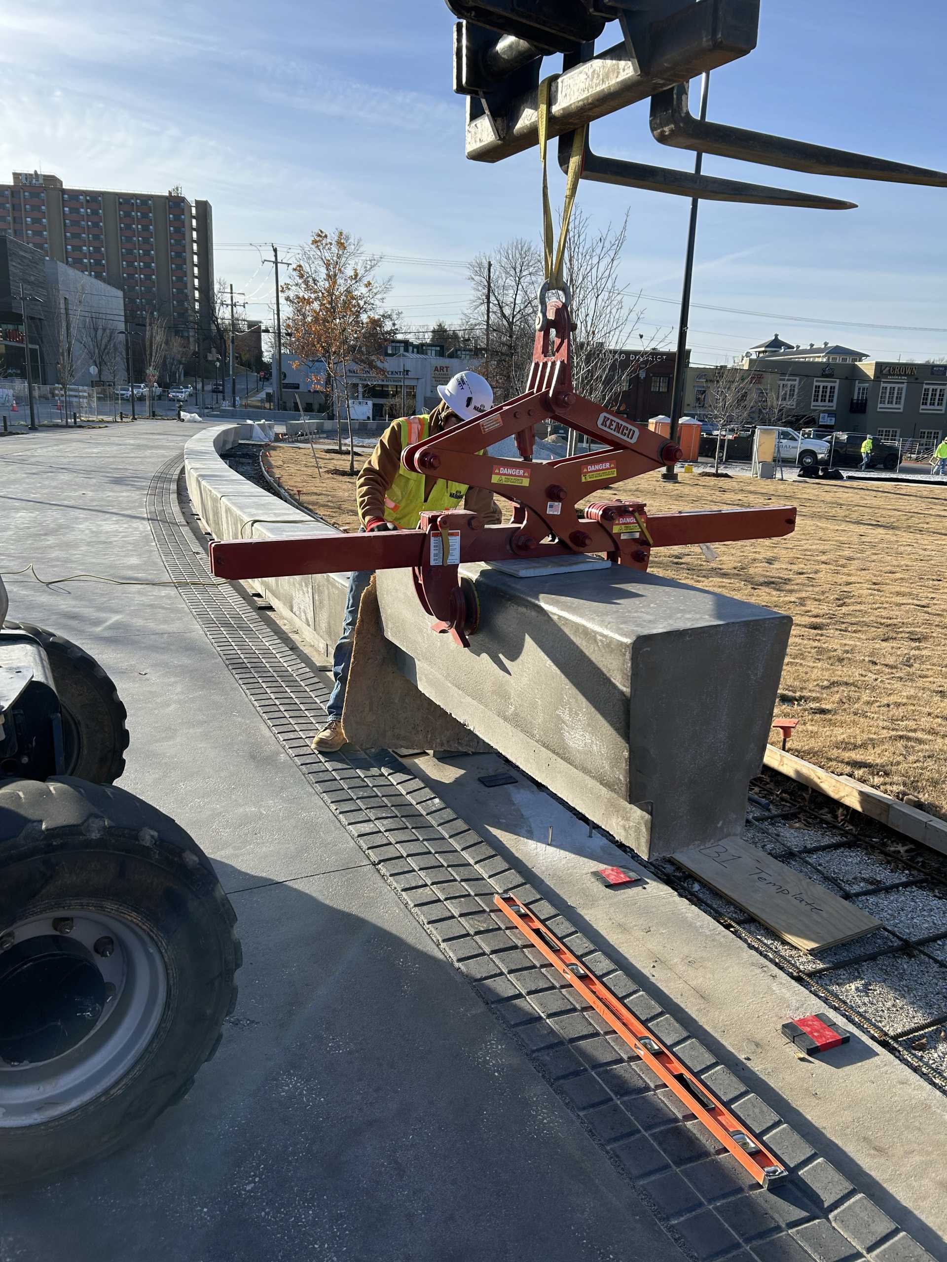 construction worker guiding the installation of concrete precast benches in a row on a jobsite