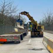 gradall machine setting concrete barrier wall at on bridge and unloading from waiting truck bed