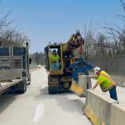 gradall machine setting concrete barrier wall at on bridge