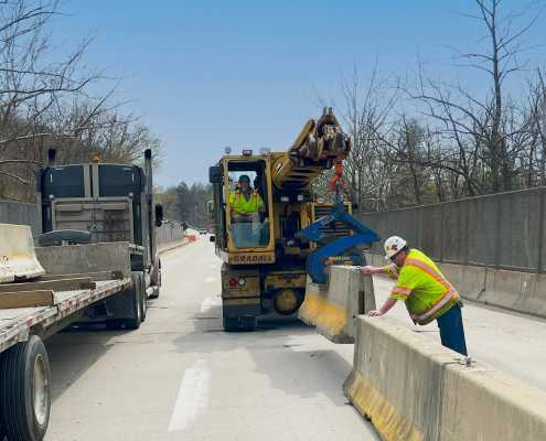 gradall machine setting concrete barrier wall at on bridge