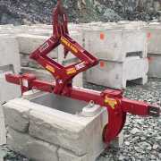 red scissor gripping tool picking up finished face retaining wall blocks
