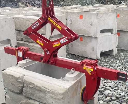 red scissor gripping tool picking up finished face retaining wall blocks