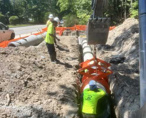 construction crew setting concrete pipe into trench using kenco pipe lifting tongs