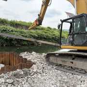 excavator with long reach boom from kenco next to the water