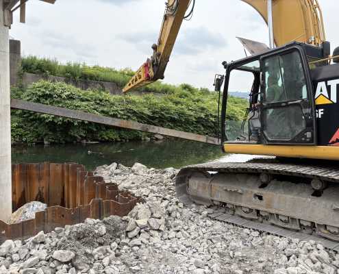 excavator with long reach boom from kenco next to the water