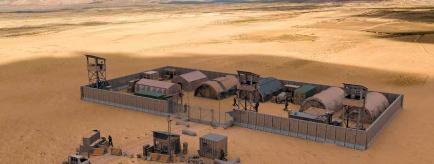 A military compound is sitting alone in the middle of a desert. It is surrounded by barriers. A truck is driving to it.