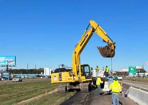 distant shot of active jersey barrier installation with work done by siema construction using a blue kenco barrier lift
