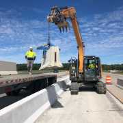 old style kenco barrier scissor clamp unloading f type precast wall from truck bed using case tracked excavator