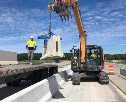 old style kenco barrier scissor clamp unloading f type precast wall from truck bed using case tracked excavator