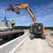old style kenco barrier lift unloading jersey wall from truck bed using case mid size excavator