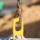 Yellow concrete block lifting hook connected to a heavy-duty steel chain above a precast barrier on an active job site.
